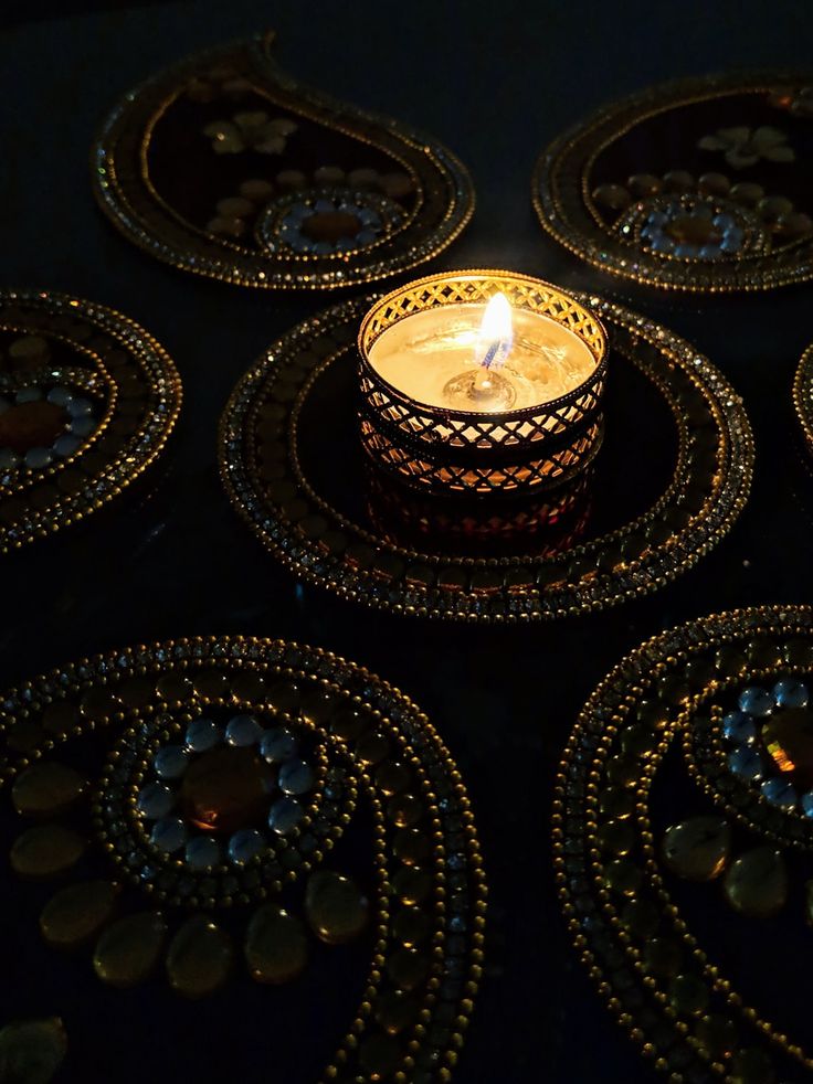 a lit candle sitting on top of a black plate covered in glass beads and beadwork