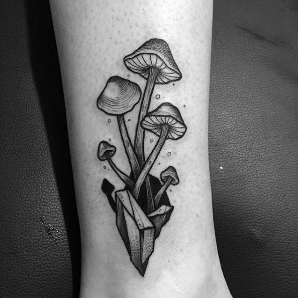 a small black and white tattoo on the leg of a woman with mushrooms growing out of it