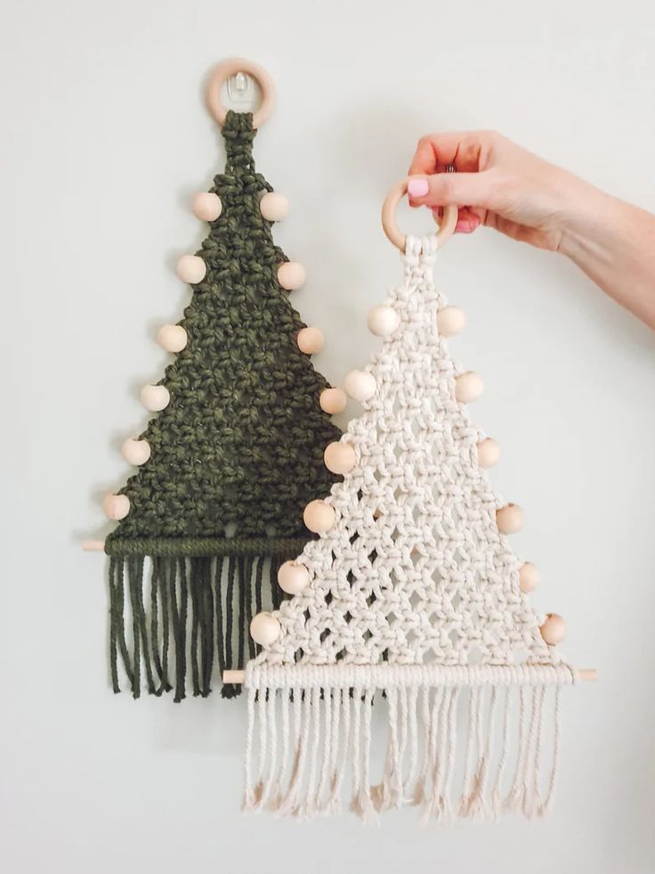 two crocheted christmas trees hanging on the wall, one is green and the other is white