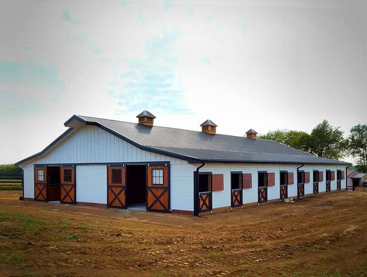 a large white barn with brown doors and windows