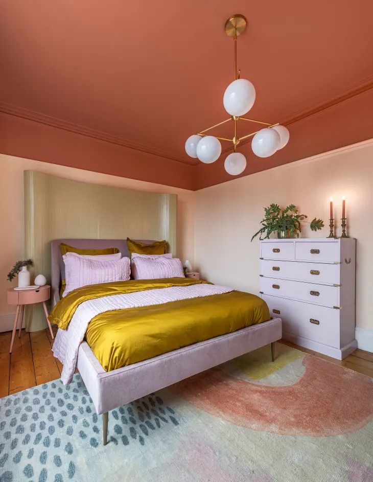 a bedroom with pink walls and gold bedding