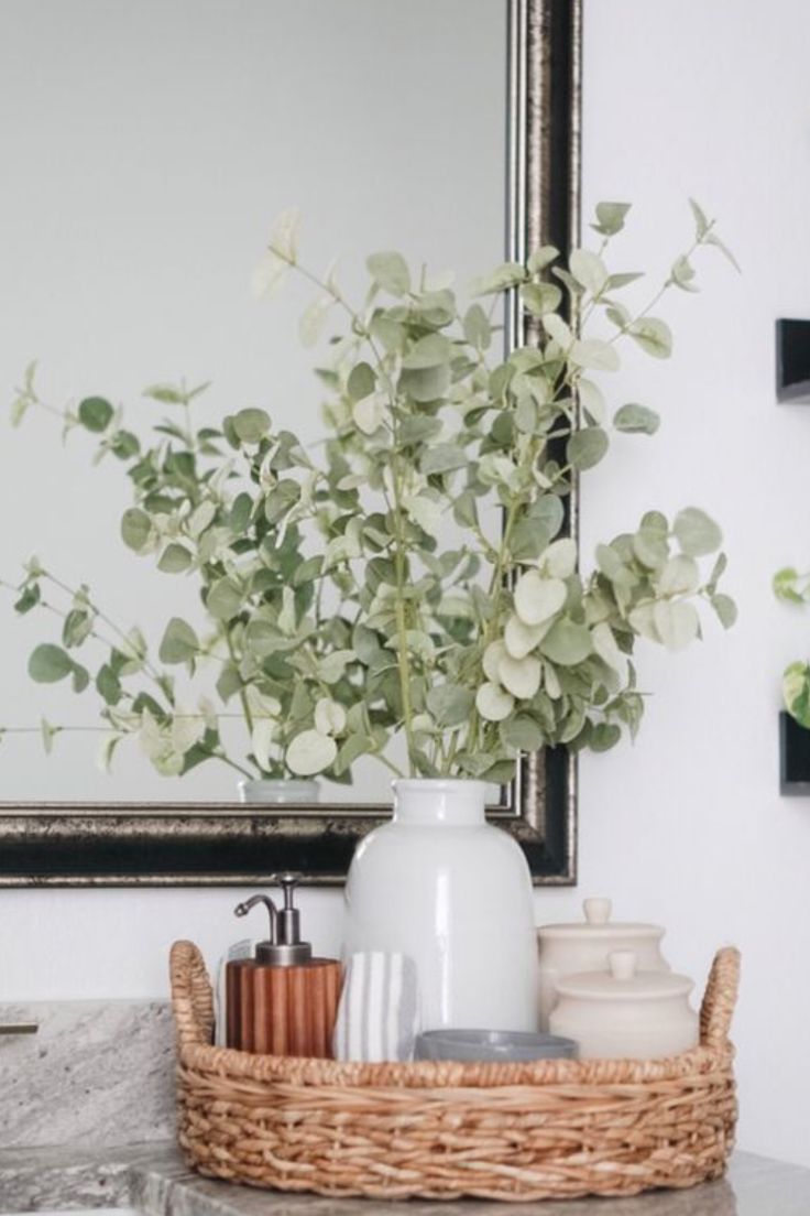 a vase with some flowers in it sitting on a bathroom counter next to a mirror