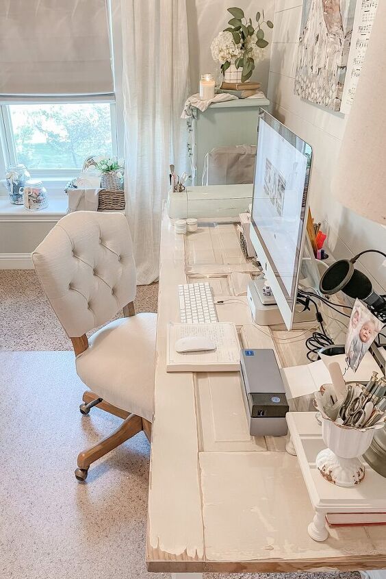 a desk with a computer, laptop and other items on it in front of a window