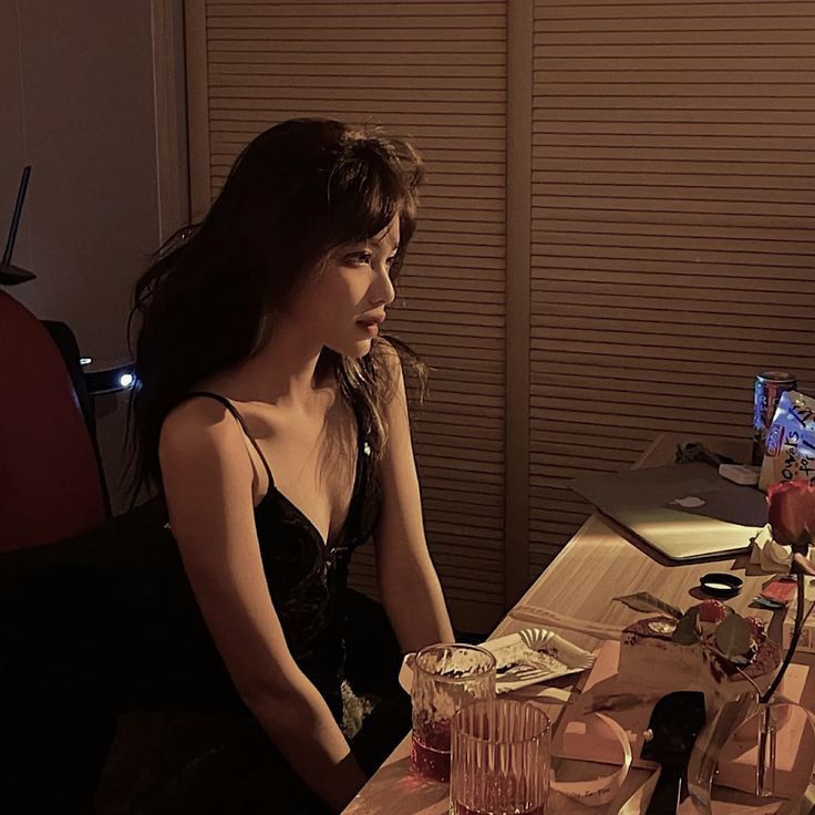 a woman sitting at a table in front of a laptop computer