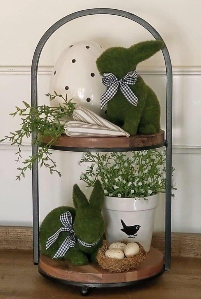 two green stuffed animals sitting on top of a shelf next to a potted plant