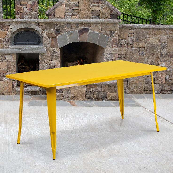 a yellow table sitting in front of a brick oven with an open fire place next to it