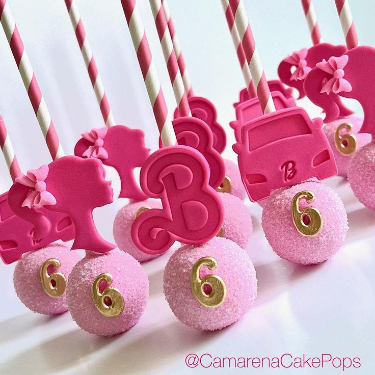 pink and gold birthday cake pops with candles in the shape of animals on wheels, decorated with bows