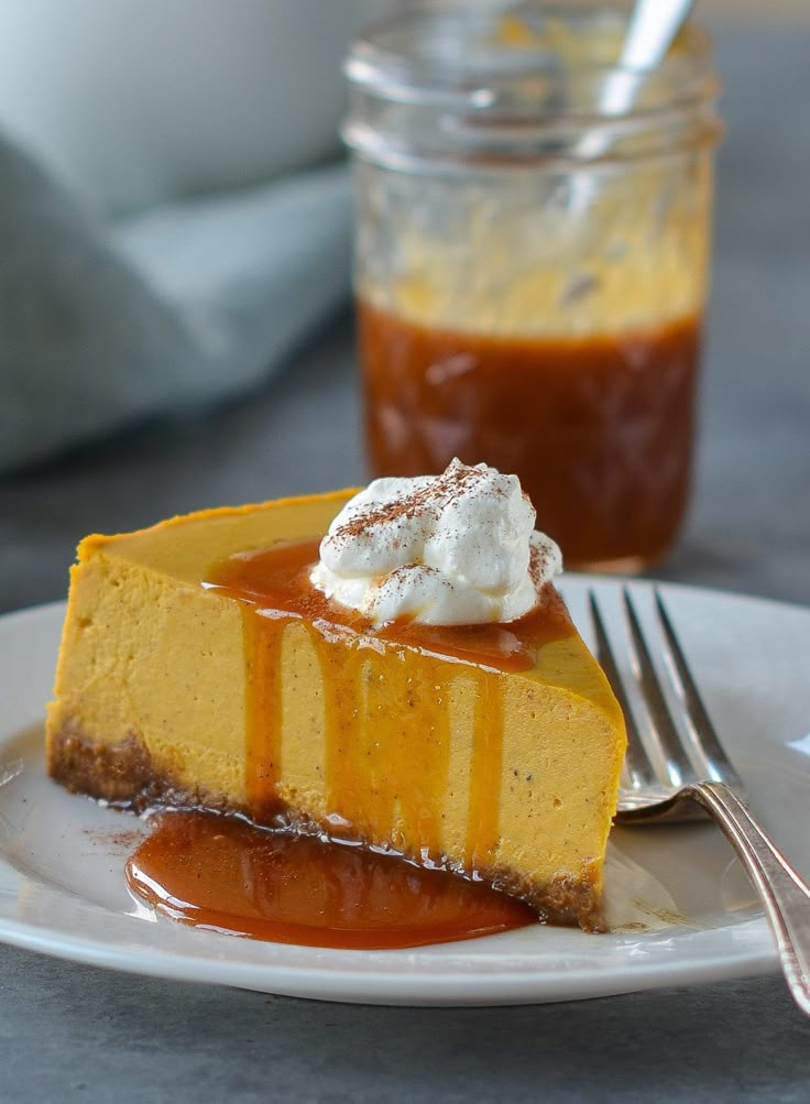 a slice of cheesecake on a plate with caramel sauce and whipped cream in the background