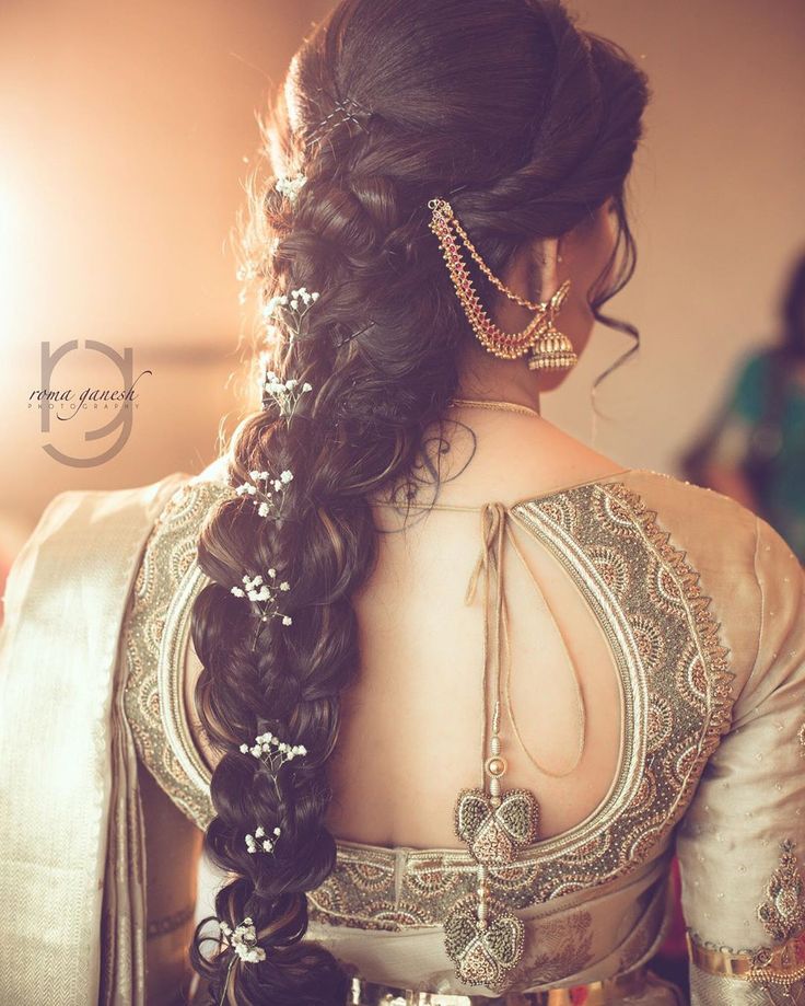 a woman with long hair wearing a white and gold sari, looking down at her back