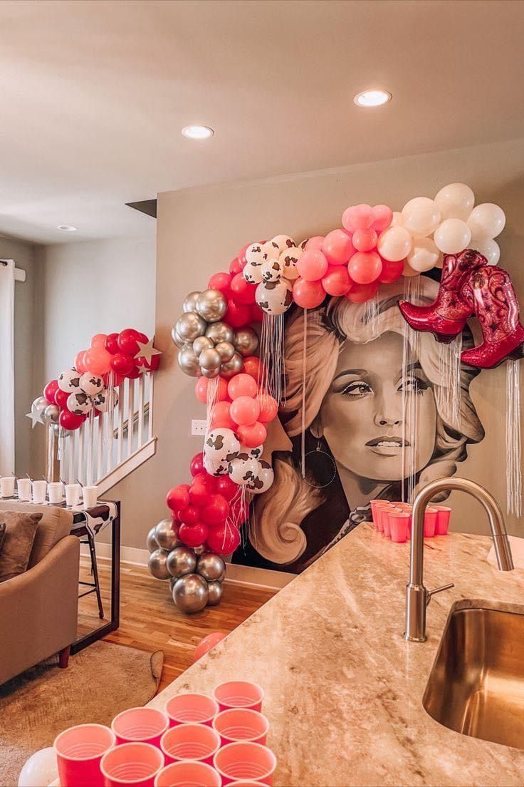 a room with balloons and decorations in the shape of a woman's face on the wall