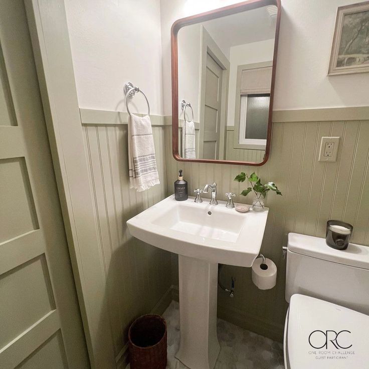 a bathroom with a toilet, sink and mirror