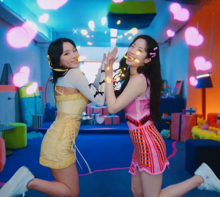 two young women are dancing in a room with bright lights on the ceiling and blue carpet