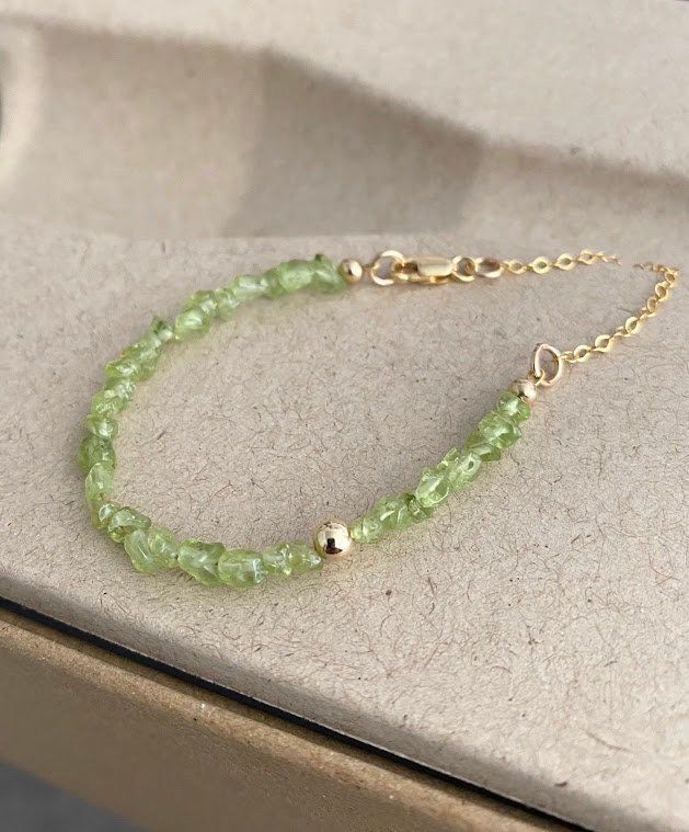 This raw peridot bracelet is available in gold filled or sterling silver.  It's layered with an off center smooth bead and finished with delicate chain and a lobster claw.  This bracelet looks great on it's own and stacks well with other bracelets. You may also like the coordinating necklace pictured in the 6th photo, link below.  A wonderful gift for an August birthday girl or a special girl on any occasion. Please select your wrist size and metal preference from the drop down menu at check out. The peridot is approx 3-6mm. You may also like to check out the coordinating necklace and more of my peridot jewelry here: https://etsy.me/2LEOuXi You may also like to check out more of my bracelets here: https://etsy.me/2KrakO6 Free first class USPS shipping within the USA. Green Gemstone Bracelet, Green Stone Bracelet, True Spring, Peridot Bracelet, August Birthday, Peridot Jewelry, Brown Bracelet, Special Girl, Delicate Chain