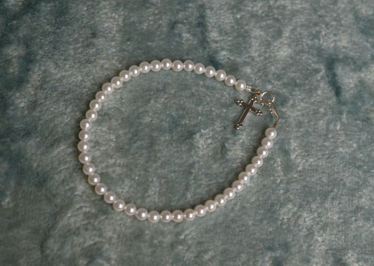 A darling silver filigree Rhodium cross graces this seed pearl bracelet that arrives in a gift box. The infant size is 4.5" and fits infant up to 2 year. Our 6" bracelet generally fits 2-9 years, and 7" fits 9-12 years. Measure her wrist just below the wrist bone to determine the best size. Our seed pearl collection necklaces and bracelets are strung by hand in Louisiana and finished with sterling silver closures. View the link below for the matching necklace. Cross Necklace Pearl White Pearl Bracelet For First Communion, Elegant Pearl Bracelet With Pearl Charm For First Communion, Adjustable Silver Pearl Bracelet For Baptism, Pearl Charm Bracelet For First Communion, Pearl Cross Necklace, Silver Cross-shaped Rosary Bracelet With 8mm Beads, Freshwater Pearl Bracelet, Pearl Collection, Seed Pearl