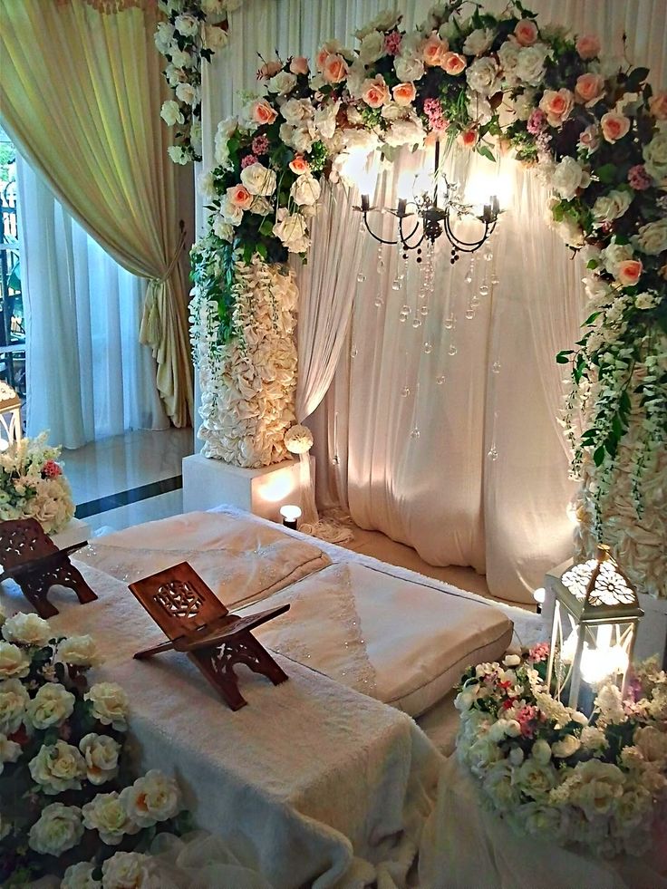 a bed covered in white flowers next to a chandelier with lights on it