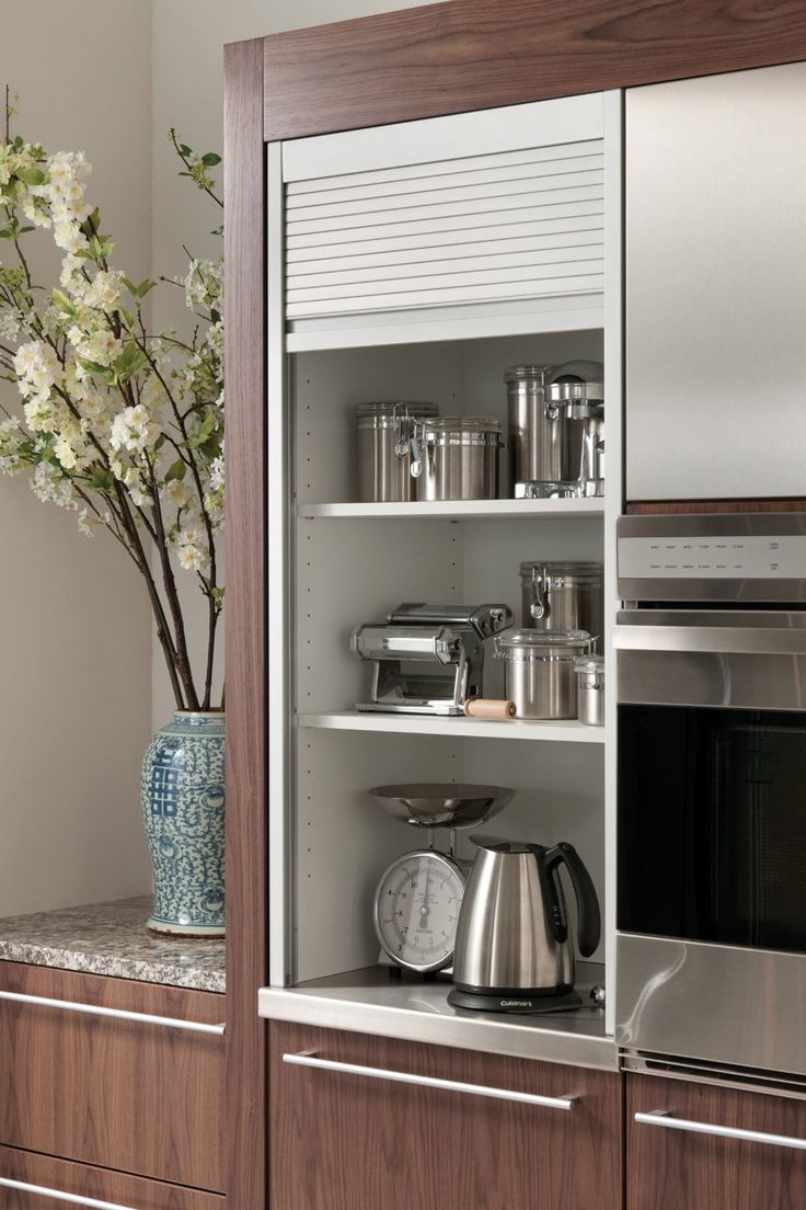 a kitchen with stainless steel appliances and wooden cabinetry, along with flowers in a vase