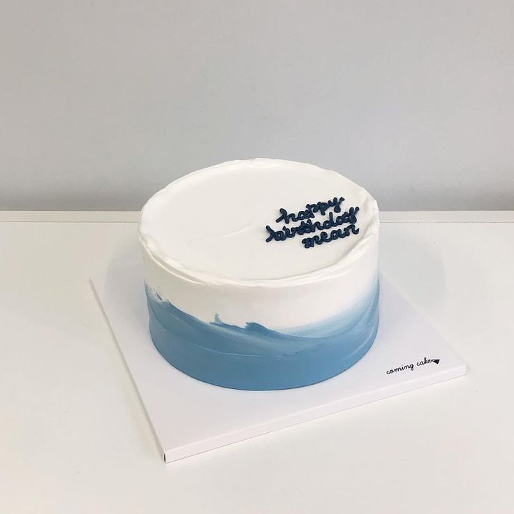 a white and blue cake with writing on it sitting on top of a card board