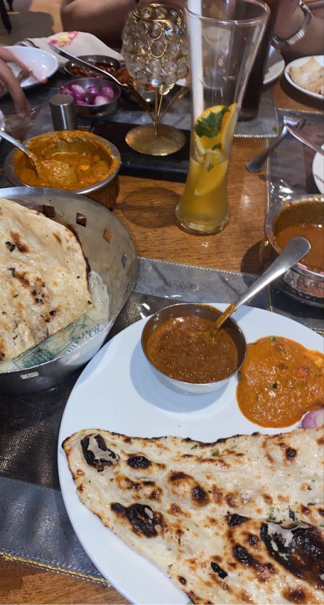 some food is sitting on a table with other plates and bowls full of sauces