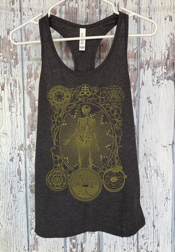 Alchemy has been many things since its incarnation, but at the heart of it all, it is the study and attraction to all magic, mysticism, and experimentation. Original design by Brad Stanfill, specializing in minimal and sacred geometry art. All designs are hand screen printed by us!Super soft lightweight preshrunk 100% cotton. Please check size chart for details!Follow us on Instagram and Tumblr for action shots of the apparel!@hexappealclothing Mystical Graphic Print Cotton Tops, Mystical Graphic Print Crew Neck Top, Mystical Cotton Tops With Graphic Print, Skull Print Crew Neck Top For Festival, Crew Neck Skull Print Top For Festivals, Halloween Festival Graphic Print Top, Cotton Tops With Skull Print For Festivals, Sacred Geometry Art, Action Shots