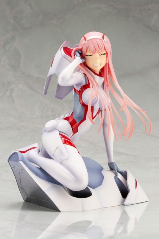 an anime figurine sitting on top of a piece of white material with pink hair