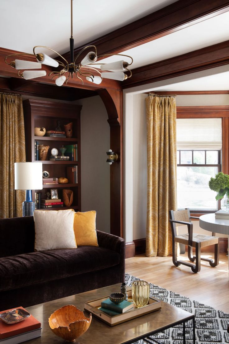 a living room filled with furniture next to a window covered in yellow and brown curtains