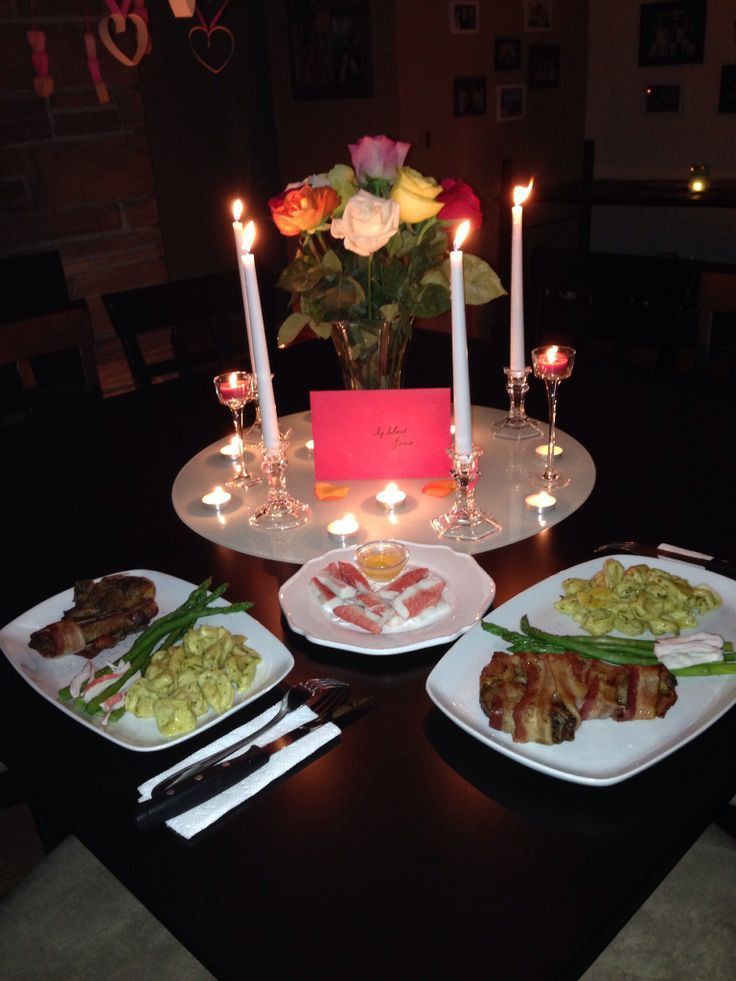 a table topped with plates of food next to candles and flowers on top of it