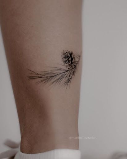 a small pine cone tattoo on the right side of the leg, it is black and white