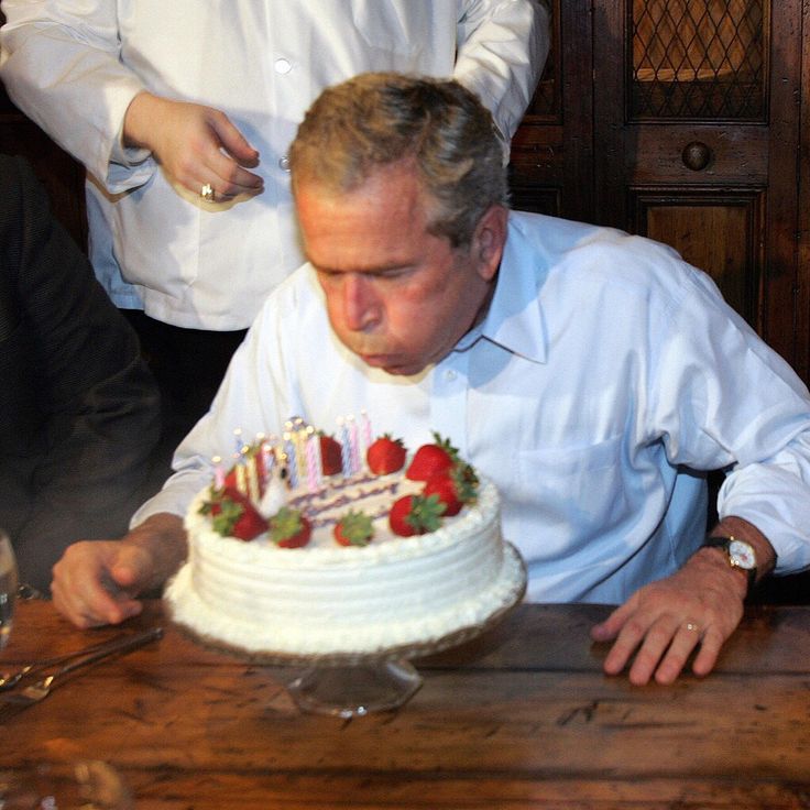 a man blowing out candles on a birthday cake that is sitting on top of a table