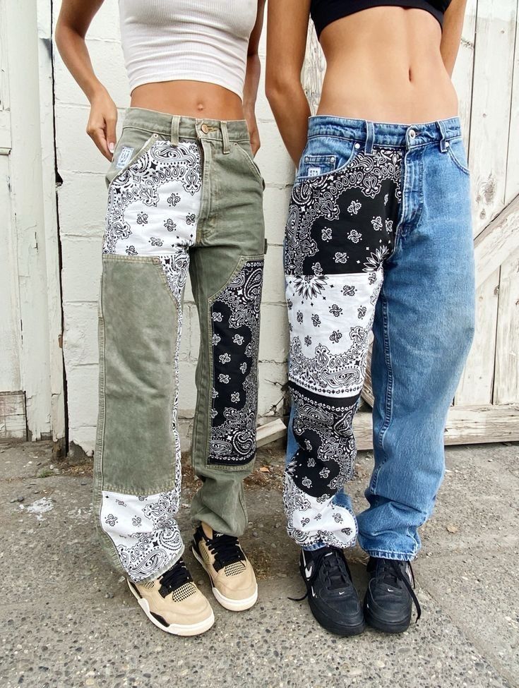 two women standing next to each other wearing jeans