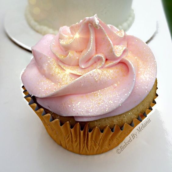 two cupcakes with pink frosting sitting on top of each other next to a white cake