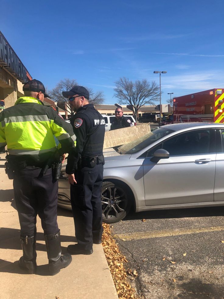 two police officers standing next to a parked car