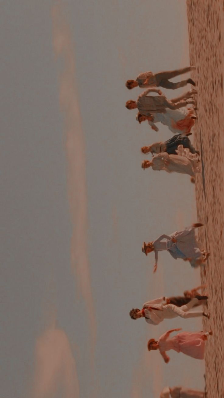 a group of people standing on top of a beach next to the ocean