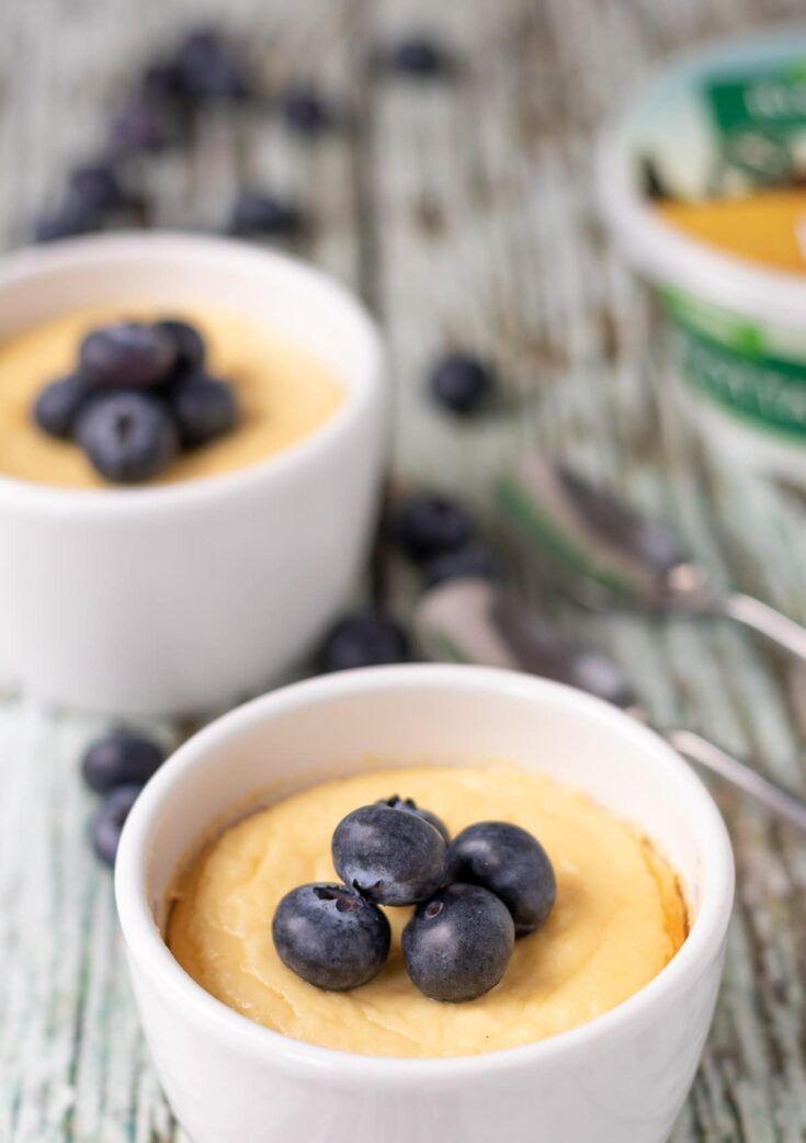 two small white bowls filled with baked vanilla ricotta pudding and blueberries on top