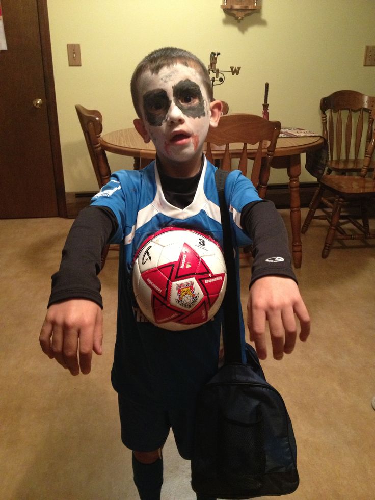 a young boy with face paint holding a soccer ball in his hands and wearing sunglasses