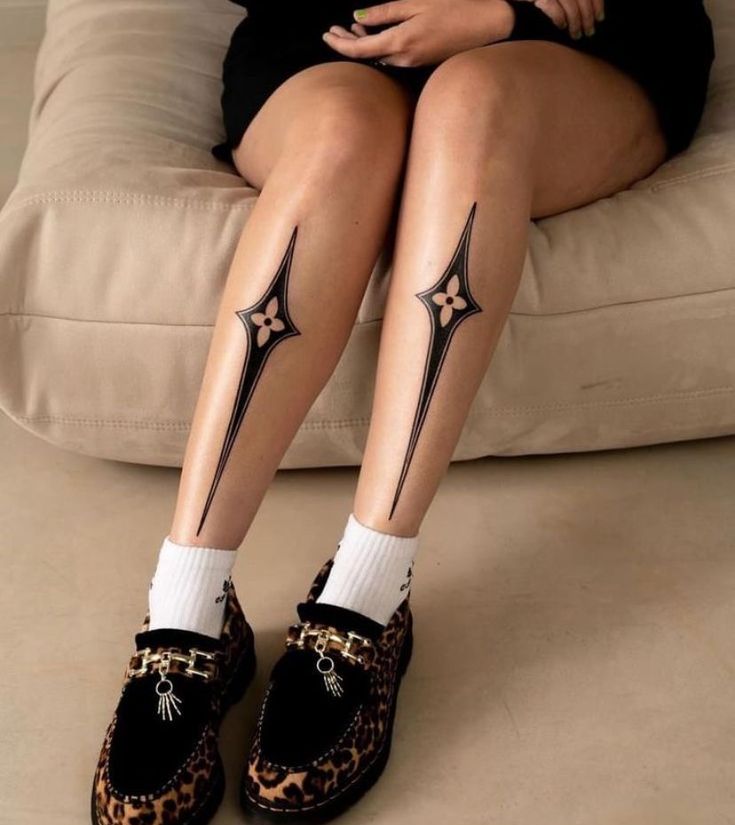 a woman sitting on top of a couch with her legs crossed and tattoos on them