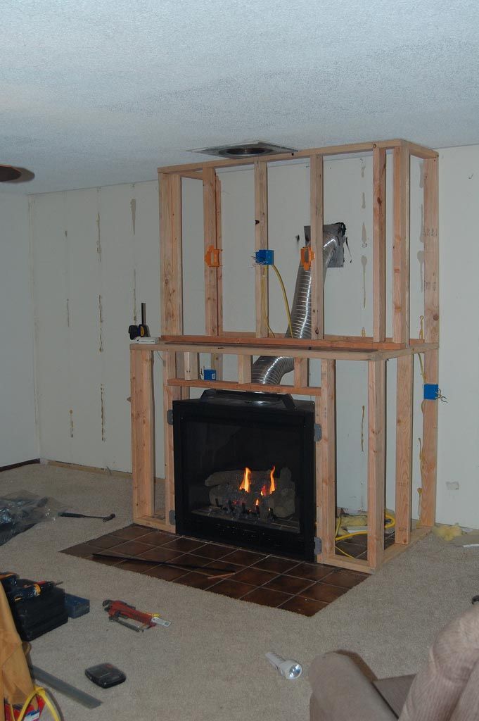 a living room with a fire place in the center and unfinished walls around it,