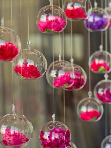 pink and red flowers in glass balls hanging from strings