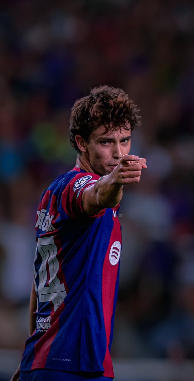 a soccer player is about to kick the ball with his hand while looking at the camera