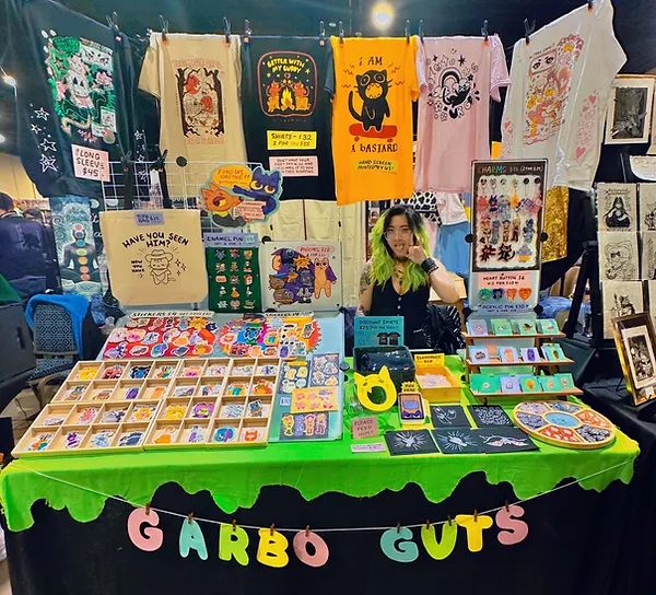 a woman standing in front of a table with cards and t - shirts on it