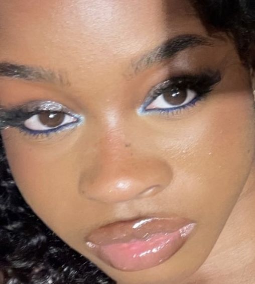 a close up of a woman with blue eyeliners on her face and curly hair