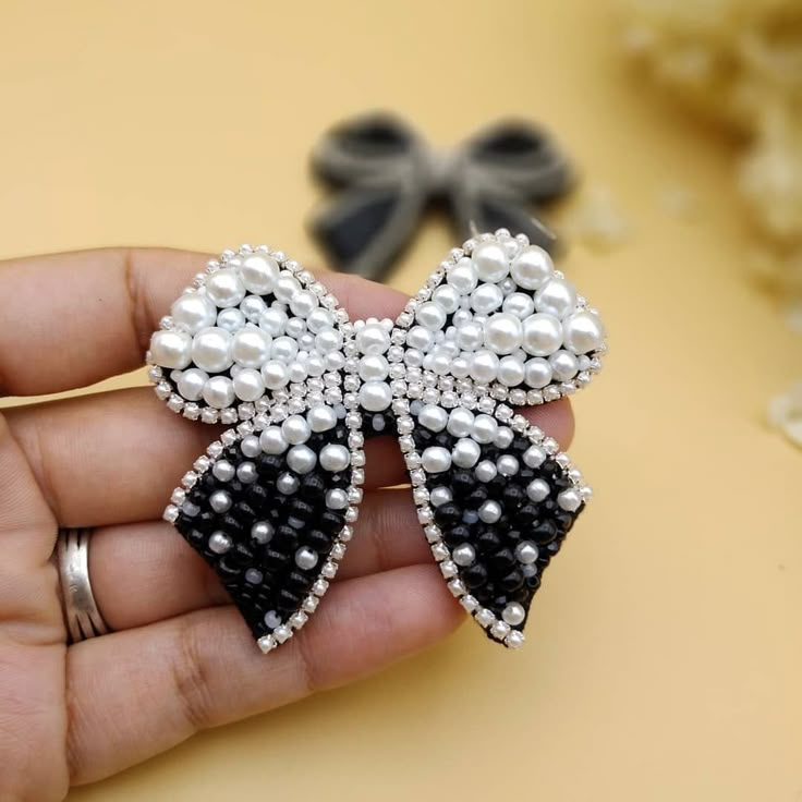 a hand holding a black and white bow brooch