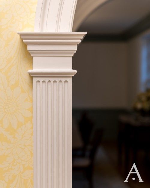 an arch in the corner of a room with yellow wallpaper