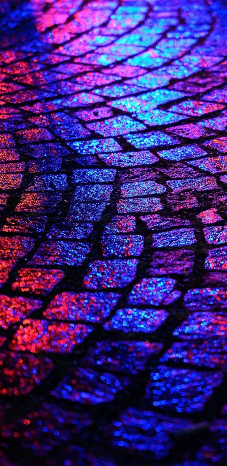 a close up view of a street with colorful lights on the pavement and cobblestones