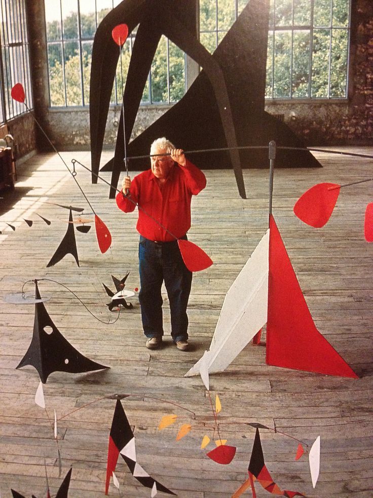 an older man is standing in front of some kites that are hanging from the ceiling