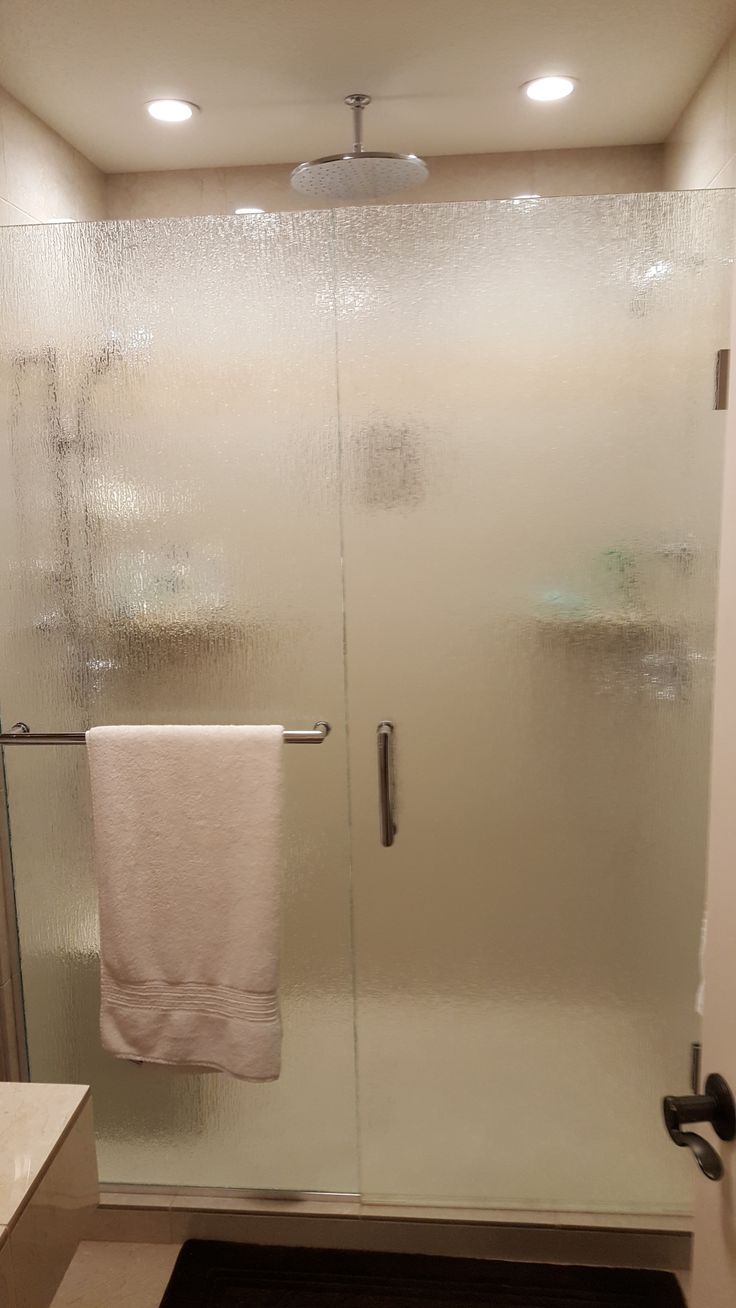 a bathroom with a glass shower door and white towels hanging on the handlebars