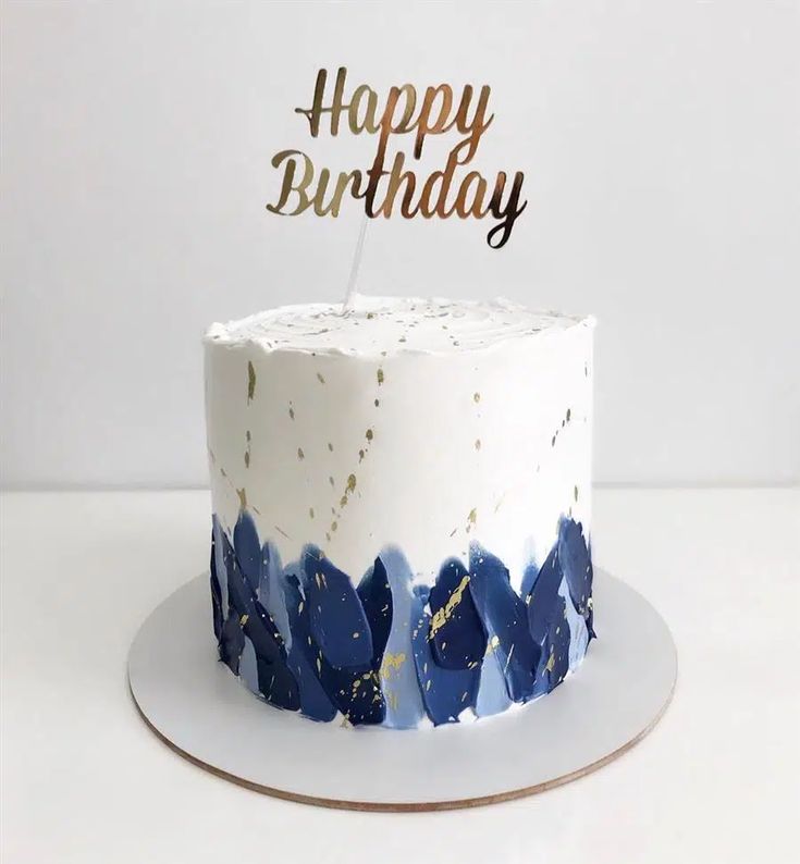 a white cake with blue and gold frosting on top that says happy birthday,