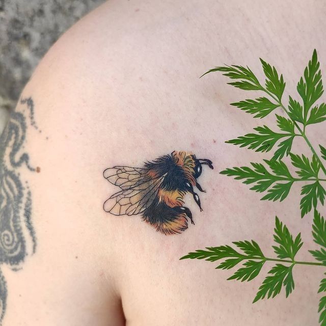 a close up of a person's chest with a tattoo of a bee on it