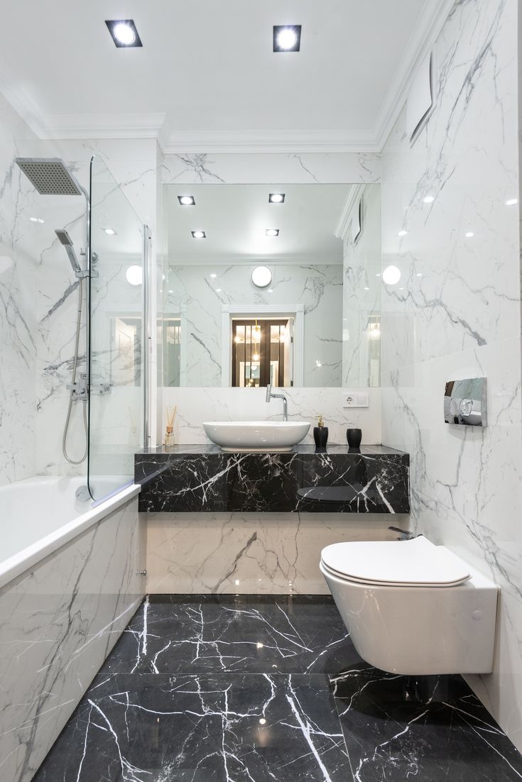 a bathroom with black and white marble on the floor, tub, sink and toilet