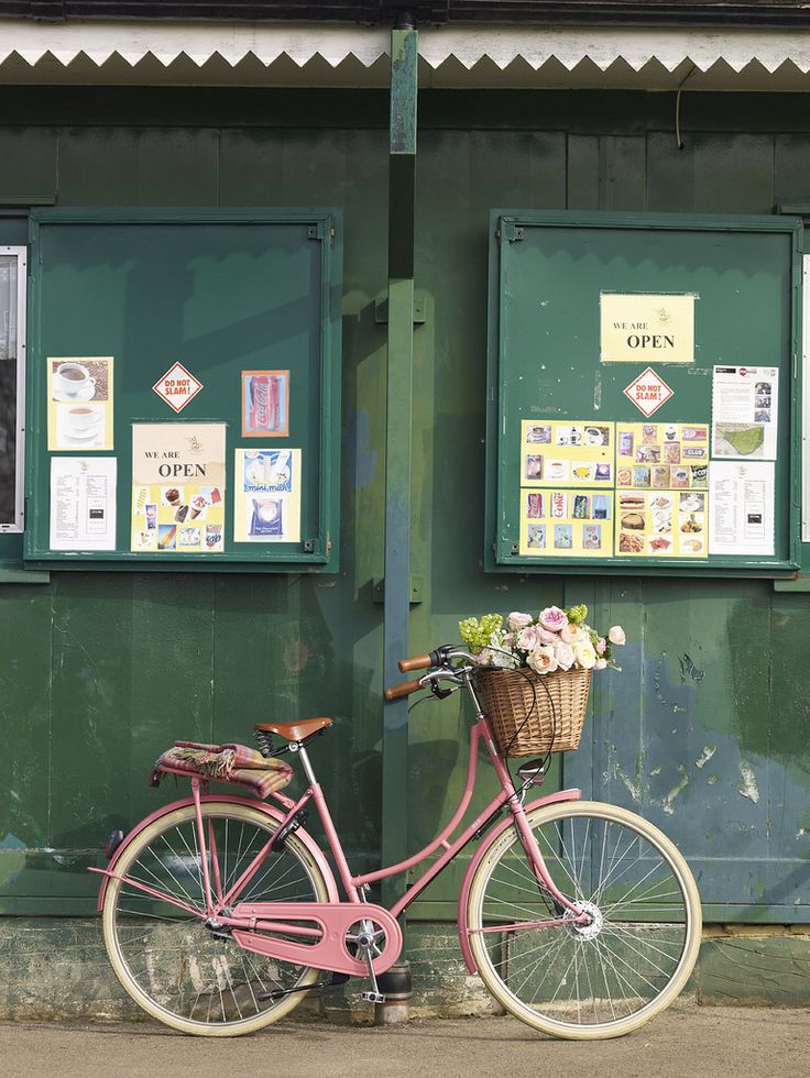 a pink bike parked next to a green building