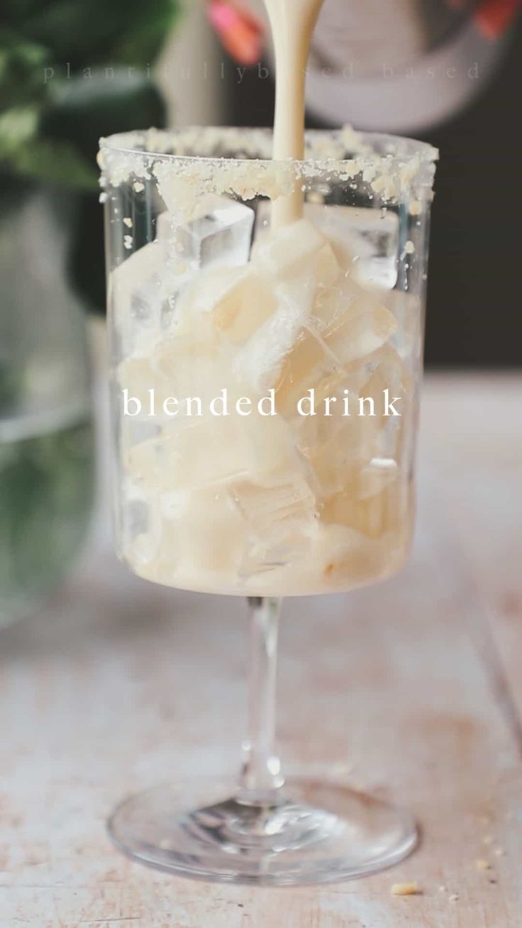 a drink being poured into a glass filled with ice